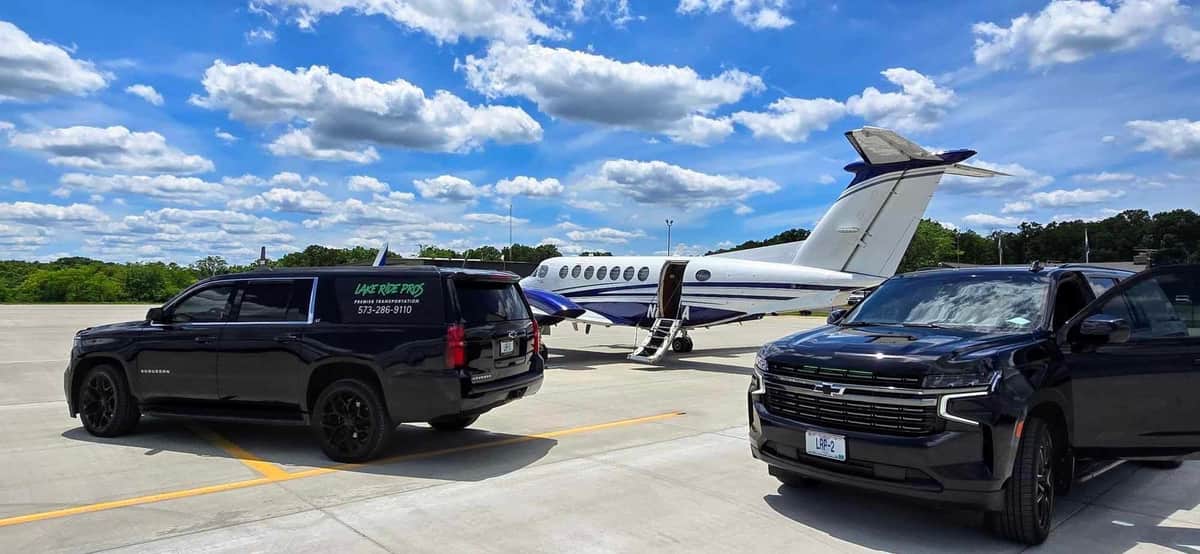 Lake Ride Pros luxury transportation fleet lined up at Lake of the Ozarks including limo bus, Rescue Squad truck, SUVs, and Mercedes Sprinter vans with lake view in background